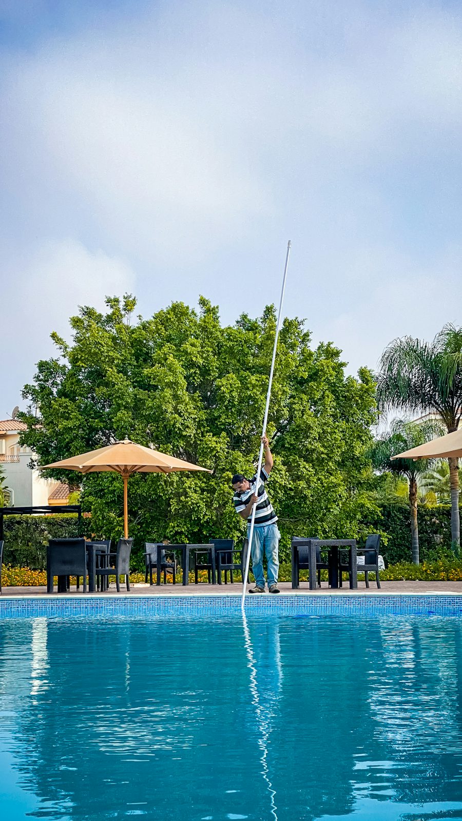 Técnico limpiando el fondo de una piscina con pértiga