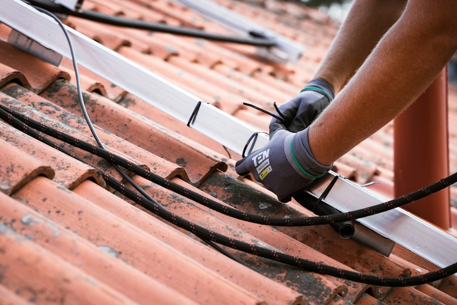 Instalador colocando el raíl de montaje de placas solares en un tejado de tejas